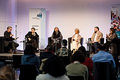 Sechs Menschen sitzen auf der Bühne und diskutieren