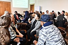 Divers aussende Menschen an verschiedenen Gruppentischen ins Gespräch vertieft